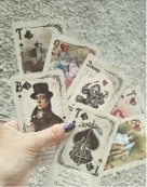 A hand holding a fan of illustrated playing cards for a reading
